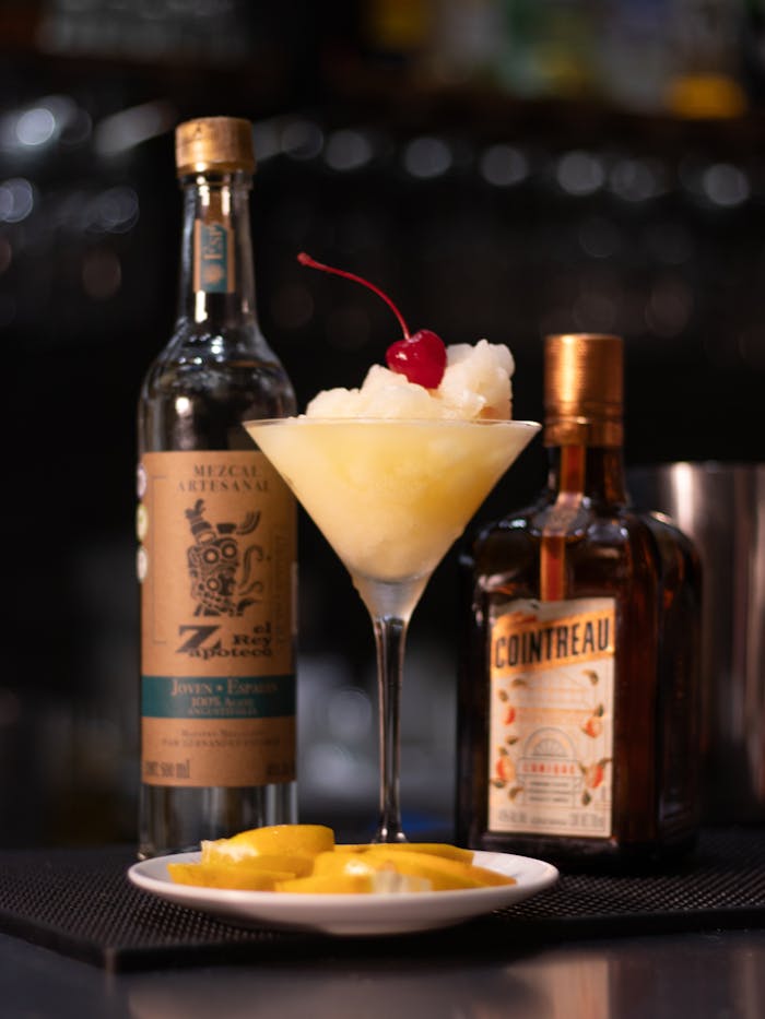 Delicious cocktail featuring mezcal and Cointreau, garnished with a cherry and served chilled.
